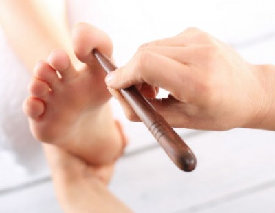 ידו של מטפל ברפלקסולוגיה לוחצת על הבוהן של רגלה של מטופלת